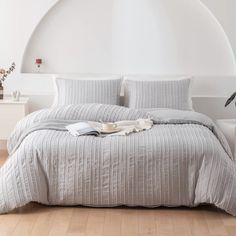 a bedroom with white walls and wood flooring has a round bed in the middle