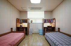 two beds in a room with wooden flooring and bookcases on the wall