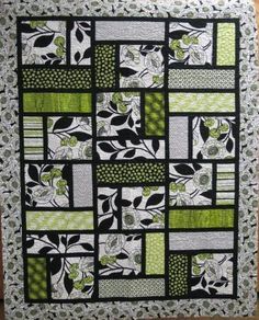 a green and black quilt with flowers on it