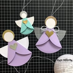 three paper angel ornaments on a table