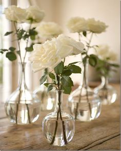 three clear vases with white roses in them