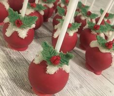 some candy apples are decorated with holly leaves and white frosting on sticks for holiday desserts