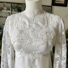 a white wedding dress on display in a room with other items and pictures behind it