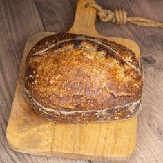 a loaf of bread sitting on top of a wooden cutting board next to a rope