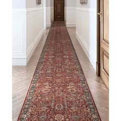 a long hallway with an ornate rug on the floor and two doors leading to another room