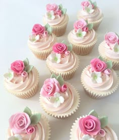 cupcakes with pink frosting and roses on them are arranged in a row