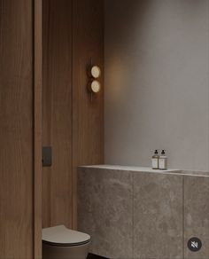 a bathroom with a white toilet sitting next to a wooden wall mounted light above it