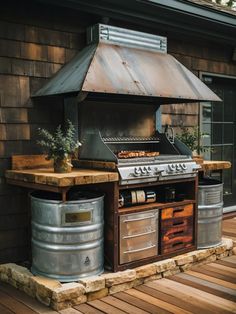 an outdoor bbq grill on a deck next to two metal pails and a potted plant