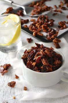 a white bowl filled with granola next to a glass of lemonade