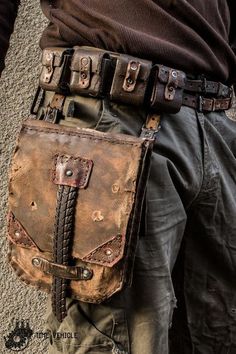 a man is wearing a brown leather belt with metal buckles on the side and his pants rolled up