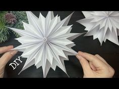 two hands are holding paper snowflakes on a table