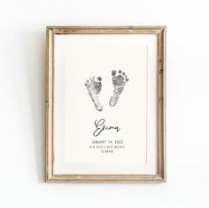 a baby's hand and foot prints are displayed in a wooden frame on the wall