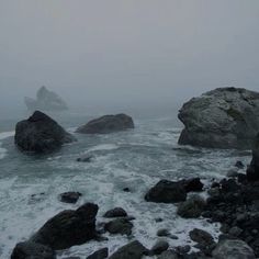 some rocks and water on a foggy day