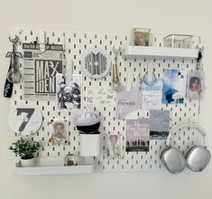 a white wall covered in magnets and pictures next to a potted plant on a shelf