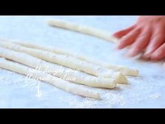 some food is being made on a table and someone's hands are touching the dough