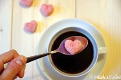 a spoon full of heart shaped sugar sitting in front of a cup of black coffee