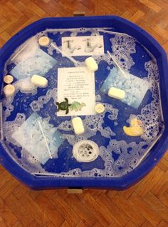 a blue bowl filled with ice and water on top of a wooden floor next to a sign