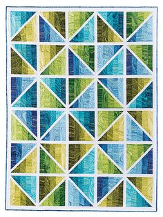 a quilted wall hanging with many different colors and shapes on the front, including blue, green, yellow, and white