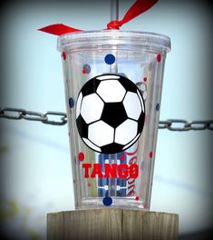 a plastic cup with a soccer ball painted on it sitting on top of a wooden post