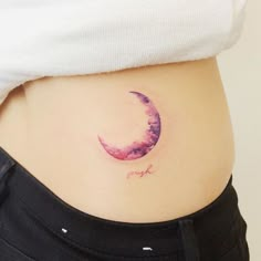 a woman's stomach with a watercolor crescent tattoo on it