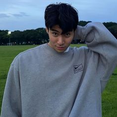 a young man standing in a field with his hands on his head