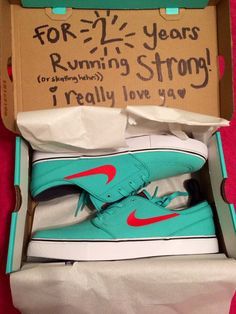 a pair of blue and red sneakers in a box on a pink surface with the words for two years running strong