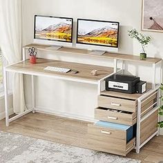 two computer monitors sitting on top of a wooden desk