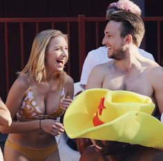 a man and woman in bathing suits laughing at each other as they stand next to one another