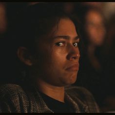 a woman looking at something in the distance with her eyes wide open while sitting down