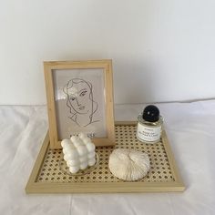 a wooden tray with some white items on it and a drawing in the frame next to it