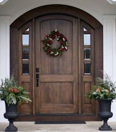 two planters with wreaths on the front door