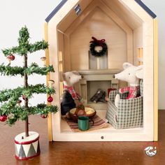 two teddy bears in a doll house with christmas decorations and a small tree on the table