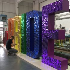 a man kneeling down in front of a giant letter made out of legos and lights