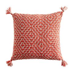 an orange and white pillow with tassels on the front, sitting against a white background