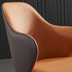 an orange and grey chair sitting in front of a black wall