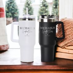 two travel mugs sitting next to each other on a table