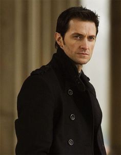 a man in a black coat looking at the camera