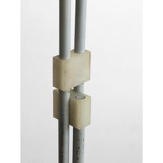 two metal poles are stacked on top of each other in front of a white wall