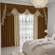 a bed sitting under a chandelier next to a window covered in drapes