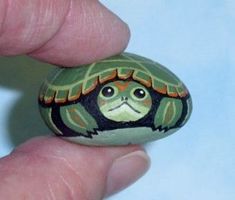 a small turtle painted on top of a rock in the palm of someone's hand