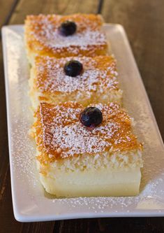 two slices of cake on a plate with powdered sugar and blueberries in the middle