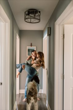 a man and woman are standing in the hallway with a dog looking at them from behind