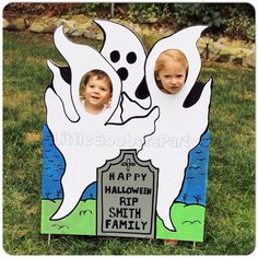 two young boys are standing in front of a halloween ghost with their faces on the tombstone