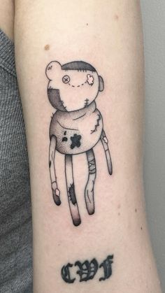 a person with a small tattoo on their arm that has an image of a teddy bear wrapped in a scarf