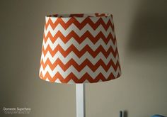 an orange and white chevron lamp shade on a desk with a blue chair in the background