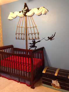 a baby's room decorated in blue and red with a pirate ship wall decal