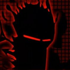 the silhouette of a person with their hand up in front of them, against a red and black background