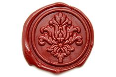 a wax stamp with an ornate design on it's front and back sides, in red