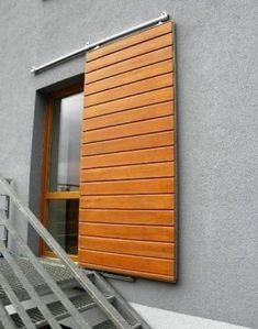 an open window on the side of a building with stairs leading up to it's door