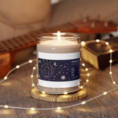 a candle sitting on top of a wooden table next to a string of lights and a guitar